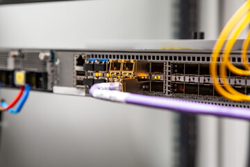 Purple patch cord inserted into the large router. SFP modules. Horizontal orientation. 