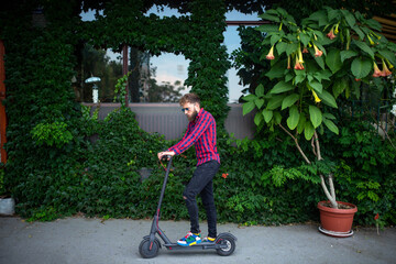Young modern man using and driving electric scooter on city street. Modern and ecological...