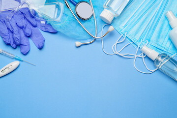 Coronavirus protection concept - latex gloves, mask, hand sanitizer syringe, stethoscope and thermometer over blue background