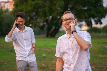 Fototapeta premium Two young business men talking on the phone in the street