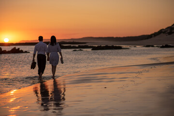 Couple walking on shoreline during golden hour