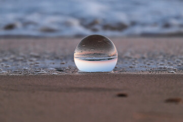 Fototapeta na wymiar sfera di cristallo sulla spiaggia al tramonto