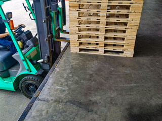 Worker driving forklift to loading and unloading wooden pallets from truck to warehouse cargo...
