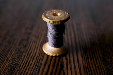 Fototapeta na wymiar Wooden spool of thread. Purple thin thread. Dark background