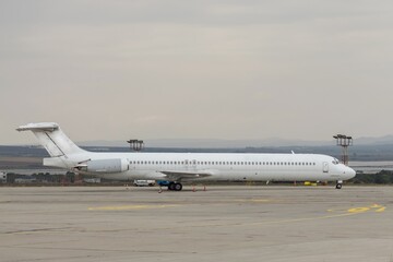 Side view of airplane. White commercial passenger jet airliner on airport apron. Cloudy sky background. Modern technology in fast transportation, business travel aviation, tourism charter flights.