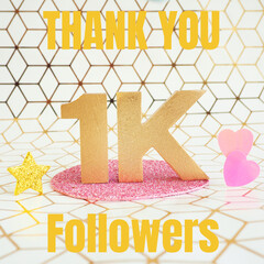 Lettering in gold volumetric letters "Thank you 1K followers" and pink plastic hearts on a white and gold geometric background..