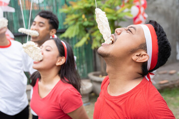 Obraz premium young men and young women competing to spend crackers during the cracker eating contest in celebration of August 17, Indonesia's independence day
