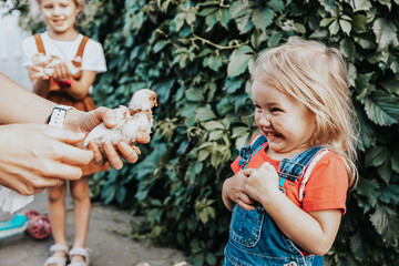 The little girl laughs cheerfully and touches the little yellow chicken on the farm. Contact petting zoo, the concept of communication between a child and animals.