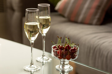 Glasses of sparkling champagne with cherries, close up. Warm colored. Celebration event, holidays, drinks concept. Companion for best family or friend's memories. Anniversary, wedding day or Christmas