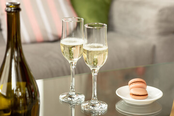 Glasses of sparkling champagne with macarons, close up. Warm colored. Celebration event, holidays, drinks concept. Companion for best family or friend's memories. Anniversary, wedding day or Christmas