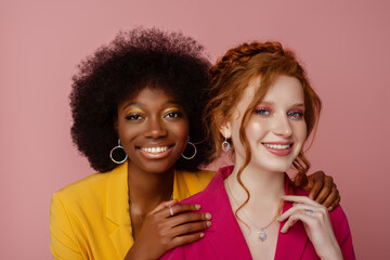 Diverse beauty, fashion: portrait of two happy smiling multiethnic women wearing colorful blazers,...