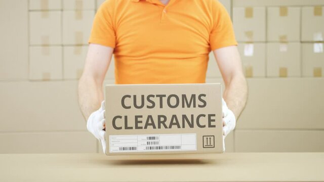 Man puts carton with CUSTOMS CLEARANCE text on the table
