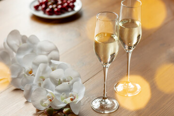 Glasses of sparkling champagne with flowers, close up. Warm. Celebration event, holidays, drinks concept. Companion for best family or friend's memories. Anniversary, wedding day or Christmas time.