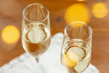 Glasses of sparkling champagne with bokeh, close up. Warm. Celebration event, holidays, drinks concept. Companion for best family or friend's memories. Anniversary, wedding day or Christmas time.