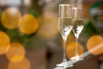 Glasses of sparkling champagne with bokeh, close up. Warm. Celebration event, holidays, drinks concept. Companion for best family or friend's memories. Anniversary, wedding day or Christmas time.