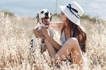Woman with a dog dalmatian in a field in summer