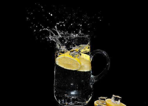 ice water splash with lemon slices isolated on black background - high speed photography