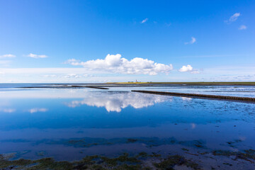 Reflection of a cloud formation on super calm North Sea with the Pellworm lighthouse in background