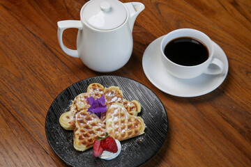 Belgian waffles served with tea on the wooden table
