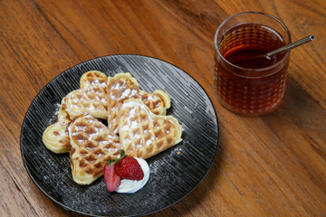 Belgian waffles served with tea on the wooden table
