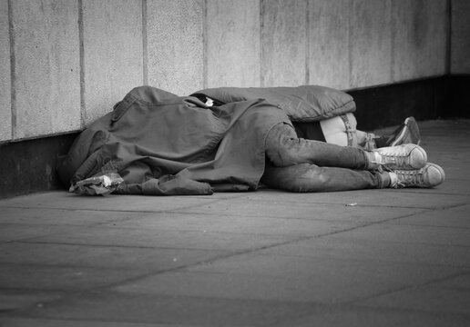 Two homeless people sleeping rough on the streets of London black and white