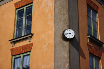 Fototapeta na wymiar A clock on the corner of a house showing the time