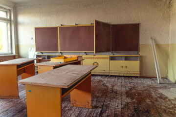 Abandoned classroom with desks and blackboard in an abandoned school