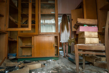 girl in a white dress with long hair and a Teddy bear in her hands stands in the terrible office of an abandoned school. Concept of horror, mysticism