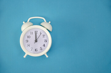 White alarm clock on blue background, copy space