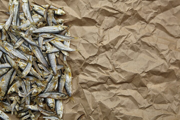 Dried small fish on crumpled paper background.
