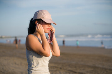 new normal running workout of Asian girl in face mask - young happy and beautiful Chinese woman jogging on the beach in post quarantine outdoors exercise