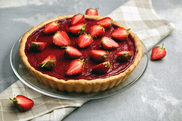 Strawberry pie decorated with fresh berries on linen napkin on grey background