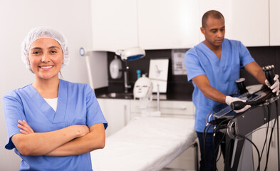 Smiling female cosmetologist standing in clinic of aesthetic medicine with arms crossed