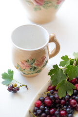 Berries in beautiful vintage dishes - still life on a white background, currants, raspberries and cherries-summer harvest. Beautiful mugs.