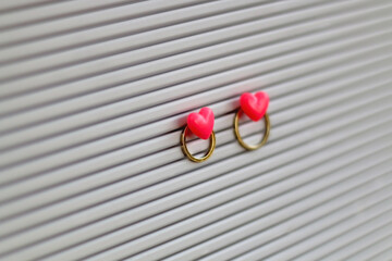 Gold wedding rings pinned with heart shaped pins on a bulletin board. Wedding concept. Selective...