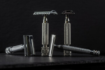 Metallic safety razors on dark background, barber shop concept