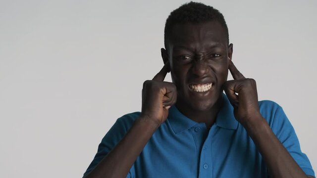 Annoyed African American man emotionally covering ears with fingers and does not want to hear anything isolated. So loud expression