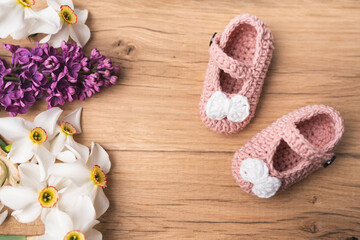 Small, hand-made shoes for a newborn baby. Needlework. Composition on oak boards. View from above. Flat Lying picture.