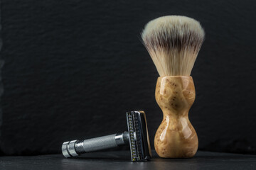 Metallic safety razors and shaving brushes on dark background, barber shop concept
