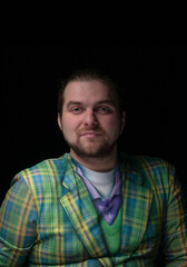 confident good looking bearded man in green plaid blazer looking at camera isolated on black