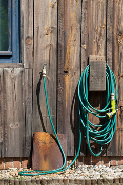 Kran z gumowym wężem na zewnętrznej ścianie drewnianego, starego domu. © AP-STUDIO