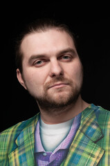 low key portrait of good looking bearded man in green blazer looking at camera isolated on black