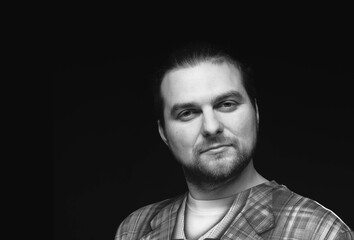 black and white portrait of good looking bearded man in checkered stylish blazer looking at camera