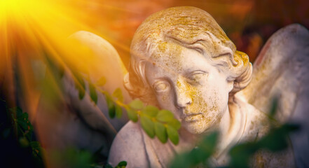 Sad eyes of angel in sunlight. Ancient stone statue. Death, pain and end of life concept.