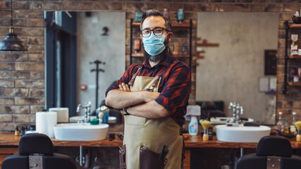 Portrait of barber at barber shop wearing protective face mask. Barber at the time of the pandemic.