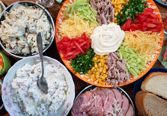 Festive table with various salads, sausage, ham