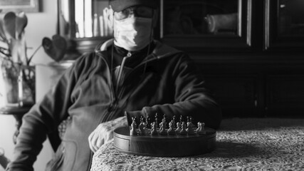Fototapeta na wymiar Covid-19 Black an white frontal half body view portrait of an old man playing chess
