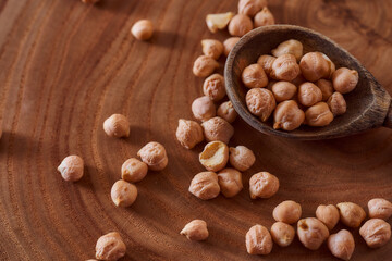 Superfood chickpeas lie in wooden background with spoon. Close-up. Top view.