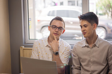 Two young men are looking at the computer with concentration