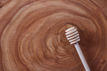 wooden honey dipper lies on a slice of a tree. wooden table. With copy space.